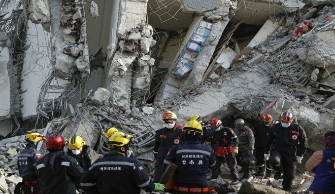 Standing below a beam of exposed oil cans used to fill space in some structures, rescuers continue to search for the missing in a collapsed building from an earthquake in Tainan, Taiwan, Sunday, Feb. 7, 2016. Rescuers on Sunday found signs of live within the remains of the high-rise residential building that collapsed in a powerful, shallow earthquake in southern Taiwan that killed over a dozen people and injured hundreds. (AP Photo/Wally Santana)